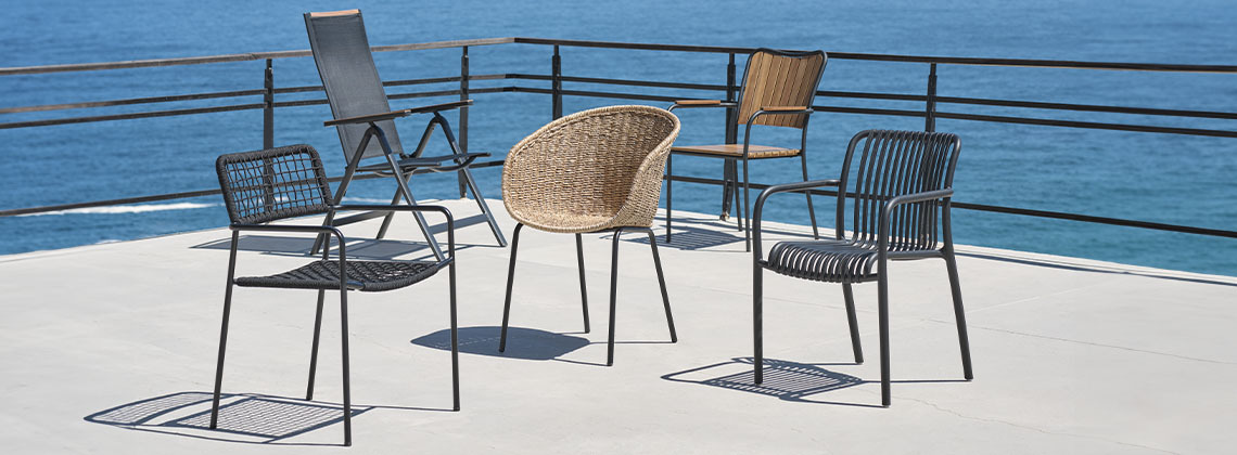 Fünf Gartenstühle auf einer Terrasse mit Meerblick 