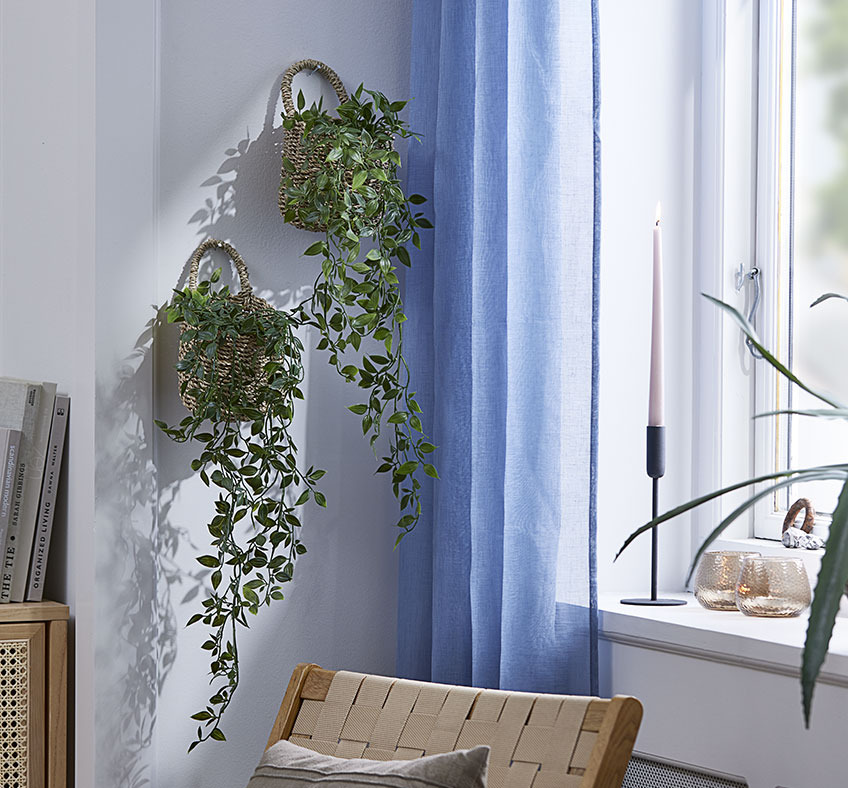 Zwei Körbe mit Kunstpflanzen an der Wohnzimmerwand